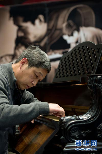 中国南京钢琴制作师张纲宁正在展会上调试钢琴